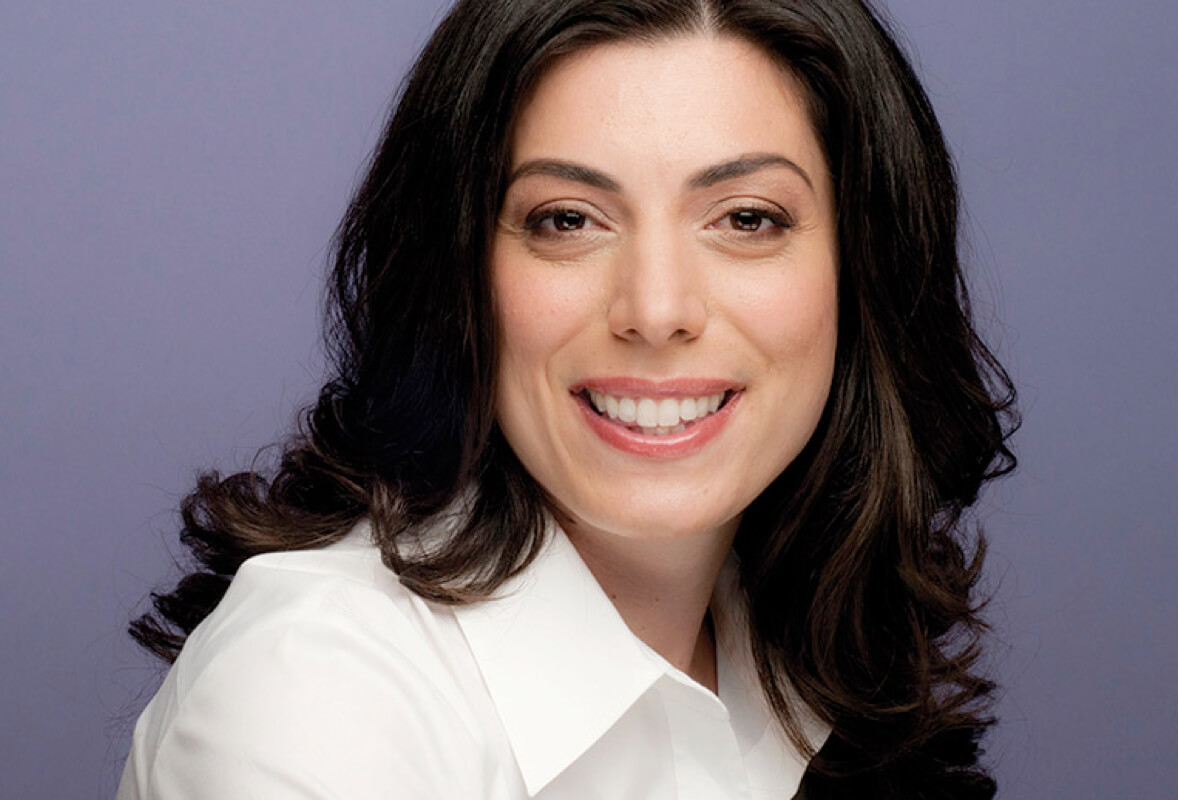 A lady wearing white shirt, smiling at the camera