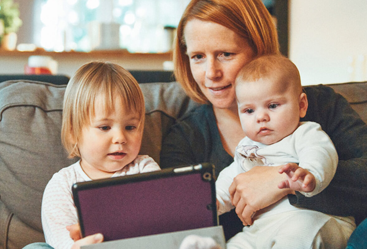 Mother with toddler and infant looking at tablet